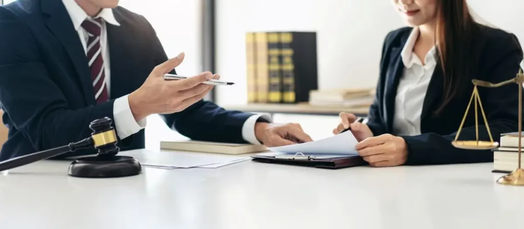 Bankruptcy attorney consulting with a client at a desk with legal documents, gavel, and scales of justice.