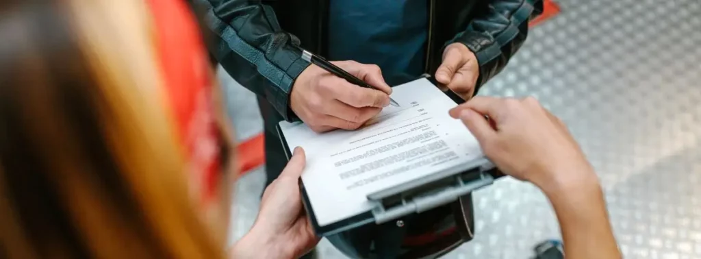 Person signing bankruptcy petition on a clipboard, representing the process of filing for Chapter 7 to achieve financial relief.
