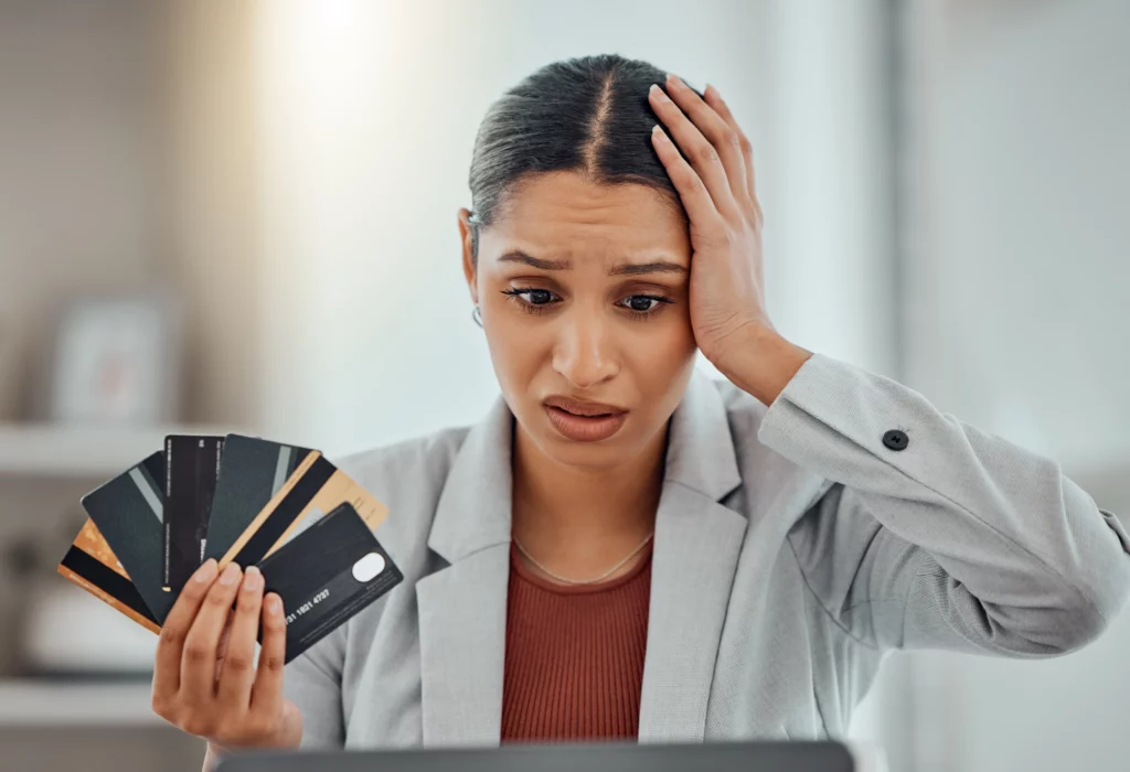 Worried woman holding credit cards and laptop illustrating concerns about unpaid credit card debt and legal consequences in Kentucky